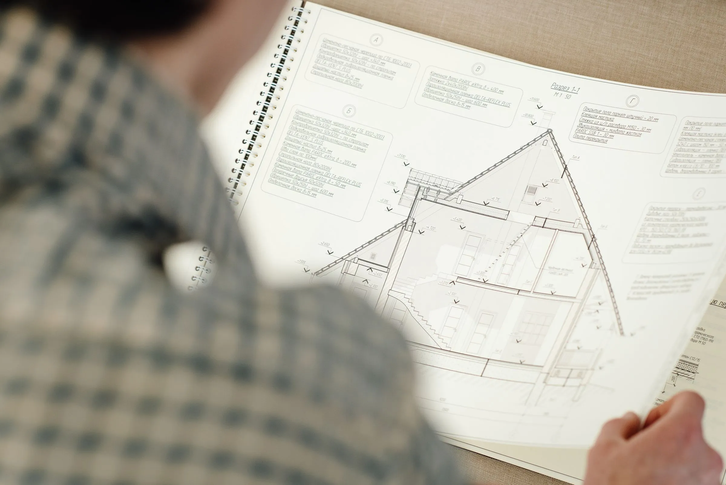 Persona che esamina i disegni tecnici di una casa per verificarne la conformità.