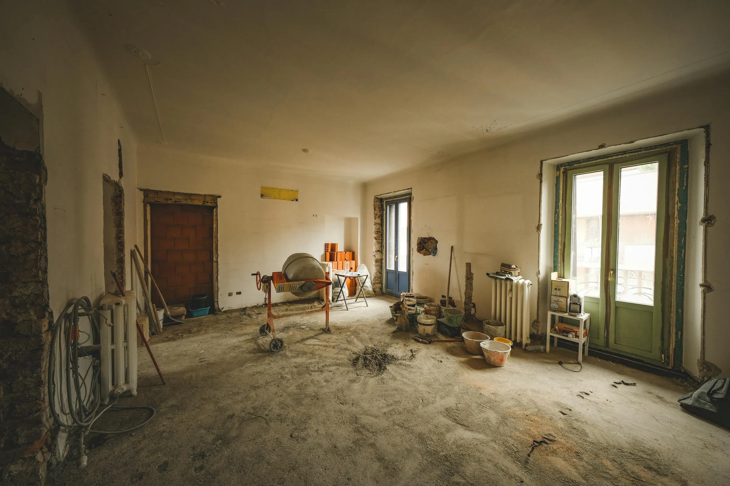 Stanza in fase di ristrutturazione con materiali e attrezzi da cantiere.