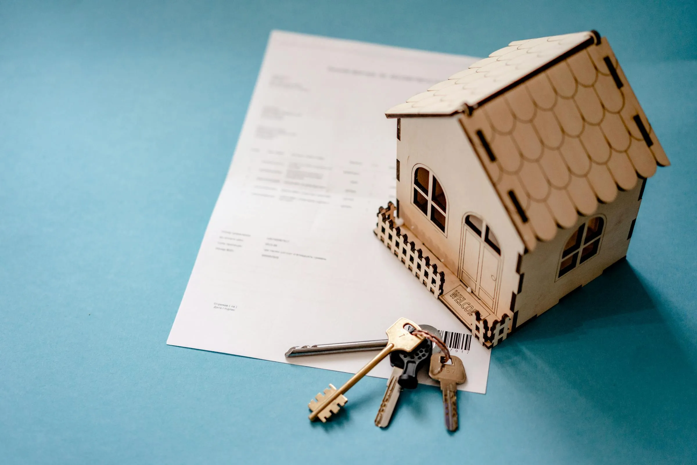 Modellino di una casa con chiavi e contratto, a richiamare le pratiche edilizie.