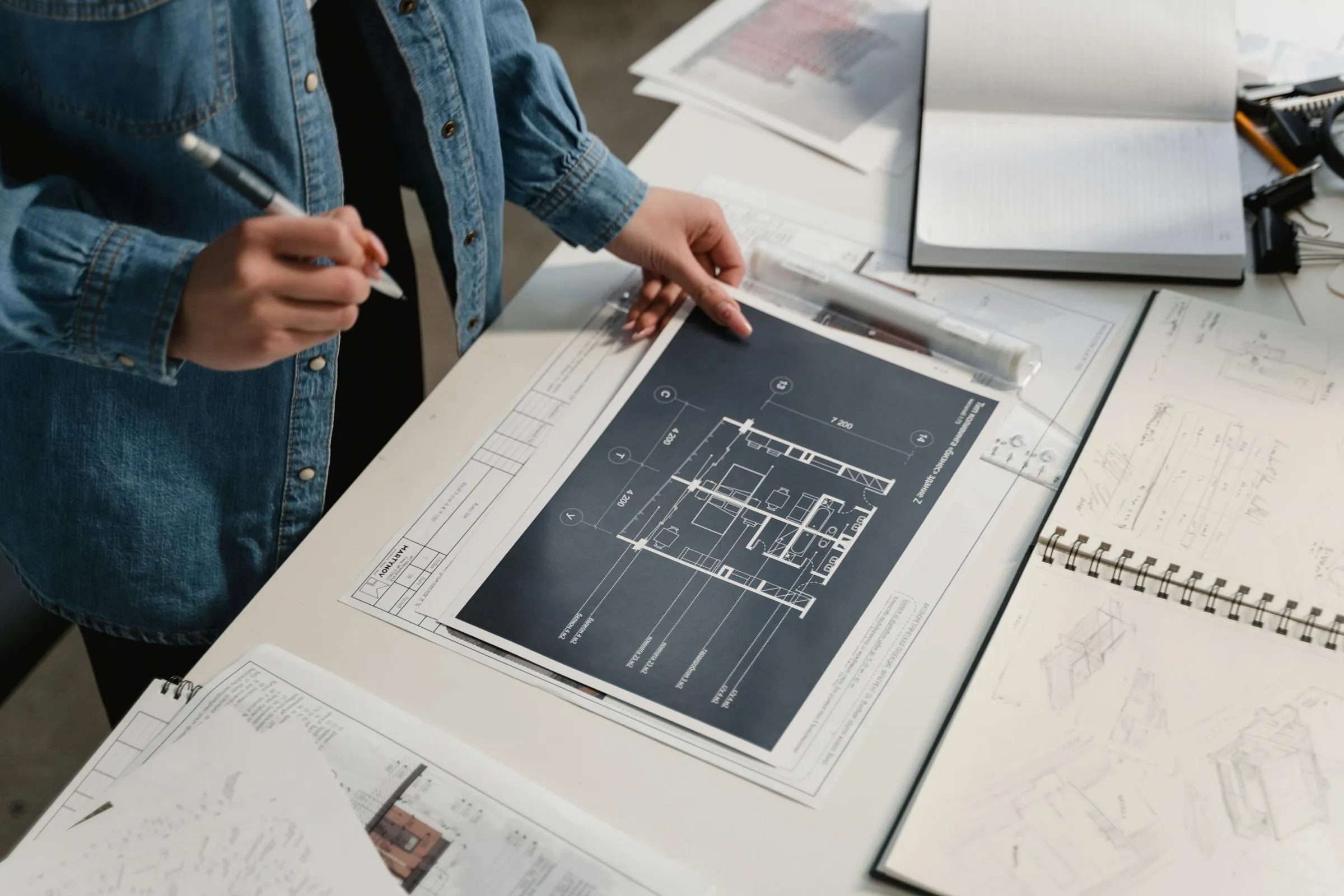 Professionista che esamina i disegni tecnici di un progetto sulla scrivania.