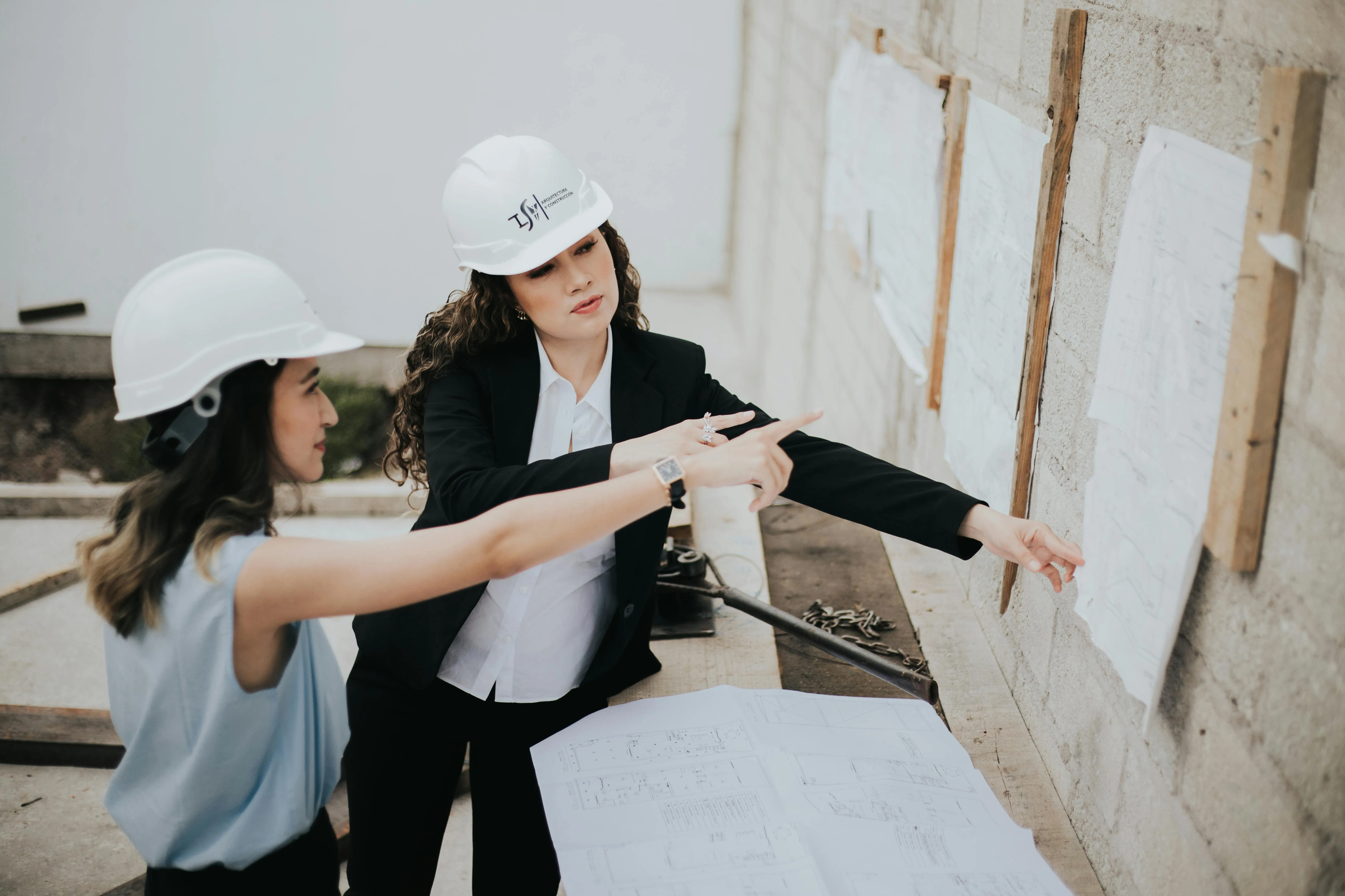 Architetto che controlla i lavori in cantiere, con casco e tavole da disegno